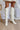 The Stephanie Boot is a tall white boot featuring a faux white leather, a 3" stacked heel, a pointed toe, and pull-on tabs. 
