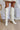 The Stephanie Boot is a tall white boot featuring a faux white leather, a 3" stacked heel, a pointed toe, and pull-on tabs. 