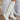 The Stephanie Boot is a tall white boot featuring a faux white leather, a 3" stacked heel, a pointed toe, and pull-on tabs. 
