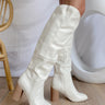The Stephanie Boot is a tall white boot featuring a faux white leather, a 3" stacked heel, a pointed toe, and pull-on tabs. 