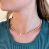Close up view of model wearing the Lucky One Necklace that features a 17" gold chain with gold beading and one pearl bead in the center.