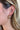 Close view of model wearing the Girl's Night Hoop Earrings that feature double open hoops with twisted details and clear rhinestones.