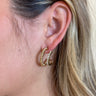 Close view of model wearing the Girl's Night Hoop Earrings that feature double open hoops with twisted details and clear rhinestones.