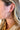 Close view of model wearing the What About Me Hoop Earrings that feature latch-back gold hoops wrapped with brown faux-leather material.