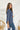 Side view of the On Your Mark Top that features a blue silky material, a collared neckline, a button-up front, and a long cuffed sleeve.