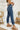 Side view of the Flying Monkey: Ease Mom Jeans that features a dark wash denim, a front button and zip closure, two front pockets, a cuffed bottom hem, two back pockets, and a mom jean fit.