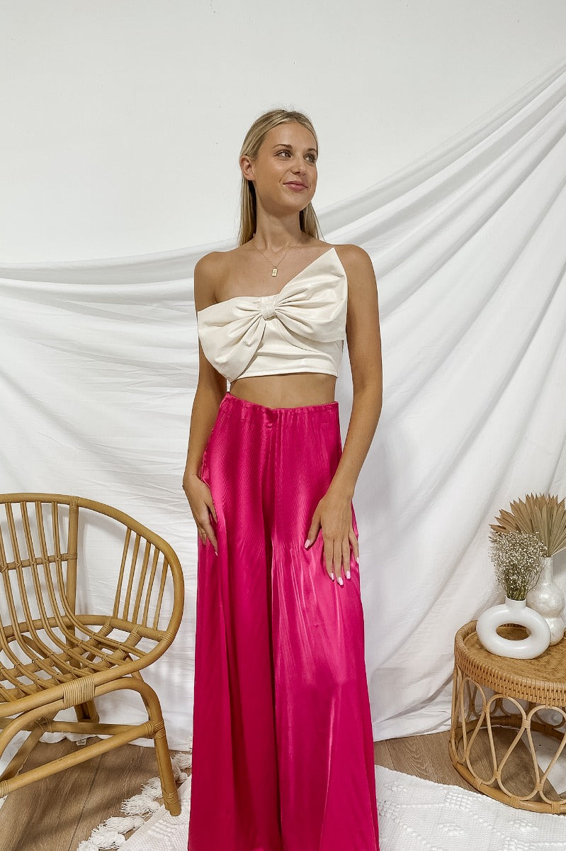 Frontal view of the My Muse Crop Top that features an ivory PU material, a sleeveless design with a straight neckline, a bow detail at the bust, a smocked back, and a cropped fit.