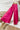 Frontal view of the High Standards Pants that features a pink silk material, a high rise fit, a thick elastic waist band, a pleated design, and a wide leg fit.