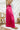 Side view of the High Standards Pants that features a pink silk material, a high rise fit, a thick elastic waist band, a pleated design, and a wide leg fit.