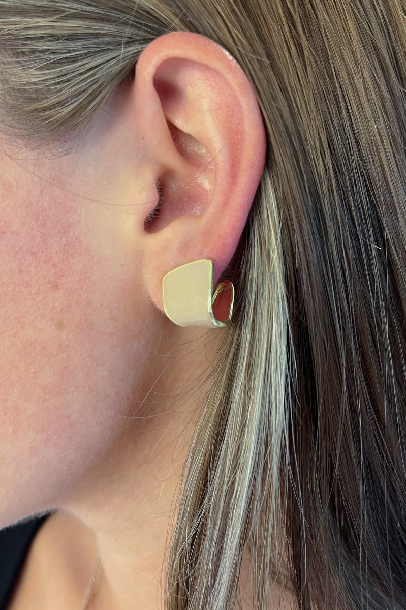 Close up view of model wearing the Keep It Classy Earrings which features scooped stud with gold and nude details.