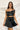 Frontal view of the My Muse Crop Top that features a black PU material, a sleeveless design with a straight neckline, a bow detail at the bust, a smocked back, and a cropped fit.