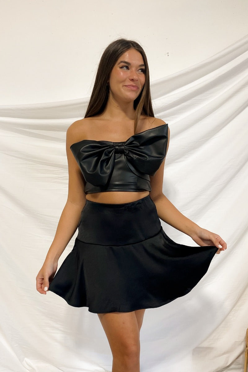 Frontal view of the Make It Mine Skort that features a black silk material, a high-rise fit, an elastic waist band, a flowy ruffle bottom, a shorts lining, and a back zipper closure.