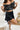 Frontal view of the My Muse Crop Top that features a black PU material, a sleeveless design with a straight neckline, a bow detail at the bust, a smocked back, and a cropped fit.