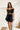 Frontal view of the My Muse Crop Top that features a black PU material, a sleeveless design with a straight neckline, a bow detail at the bust, a smocked back, and a cropped fit.
