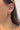 Side view of model wearing the Out Of Line Hoops which features open, small hoops covered with gold bars design.