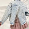 Back view of the Born Lucky Denim Jacket that features a light washed denim material, a collard neck, mild distressing, fading, front flap, two front pockets, a frayed hem, V cut open back with beaded fringe detailing
