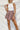 Frontal view of the Out On The Town Skort that features a mauve colored material, a high-rise fit, a thick elastic waist band with a ruffle detail, a ruffled tiered design, a shorts lining, and a mini length.