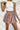 Frontal view of the Out On The Town Skort that features a mauve colored material, a high-rise fit, a thick elastic waist band with a ruffle detail, a ruffled tiered design, a shorts lining, and a mini length.
