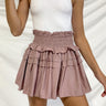 Frontal view of the Out On The Town Skort that features a mauve colored material, a high-rise fit, a thick elastic waist band with a ruffle detail, a ruffled tiered design, a shorts lining, and a mini length.