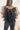 Back view of the Mirror Mirror Top that features a black sheer fabric, a rounded neckline with a sheer lining at the chest, a sheer puffy half sleeve, a flowy fit, and a button back.