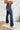 Side view of the Rooted Denim: Elodie Bootcut Jeans that features a dark wash denim, a front button and zipper closure, two front pockets, two back pockets, and a bootcut fit.