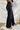 Side view of the Rooted Denim: Crue Flare Jeans that features a faded black wash denim, a front two button and zip closure, two front pockets, a frayed bottom hem, two back pockets, and a flare fit.