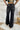 Back view of the Rooted Denim: Crue Flare Jeans that features a faded black wash denim, a front two button and zip closure, two front pockets, a frayed bottom hem, two back pockets, and a flare fit.