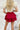 Back view of the Maeve Skort that features a red satin material, a thick elastic waist band with a tie detail, a ruffle tiered design, a shorts lining, and a mini length.