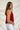Side view of the Unwritten Tank Top that features a red material, a halter neck, a sleeveless design, a pointed front and back, and a flowy fit.