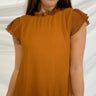 Frontal view of the Hampton Social Top that features a caramel material, a high rounded neckline with a ruffle hem, a short flowy sleeve, a pleated design, a lettuce edge bottom hem, and a flowy fit.