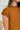 Frontal view of the Hampton Social Top that features a caramel material, a high rounded neckline with a ruffle hem, a short flowy sleeve, a pleated design, a lettuce edge bottom hem, and a flowy fit.