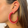Side view of model wearing the Full of Life Earrings which features open, large size hoop with orange, hot pink, light pink and gold beads.