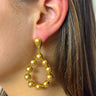 Side view of model wearing the Never Enough Earrings which features gold round beads attached to a tear-drop shaped dangle earring.