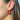 Side view of model wearing the Star Gazing Earrings in Red which features small open red hoop with white and blue stars design outlined in gold details.