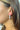Side view of model wearing the Star Gazing Earrings in White which features small open white hoop with red and blue stars design outlined in gold details.