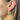 Side view of model wearing the Star Gazing Earrings in White which features small open white hoop with red and blue stars design outlined in gold details.