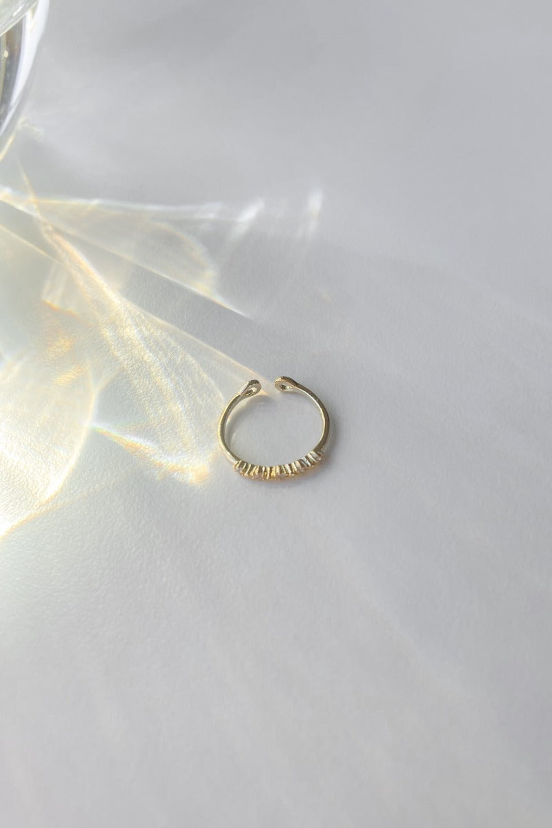 Flat lay of the Walk of Fame Ring which features a gold band with mini clear stones.
