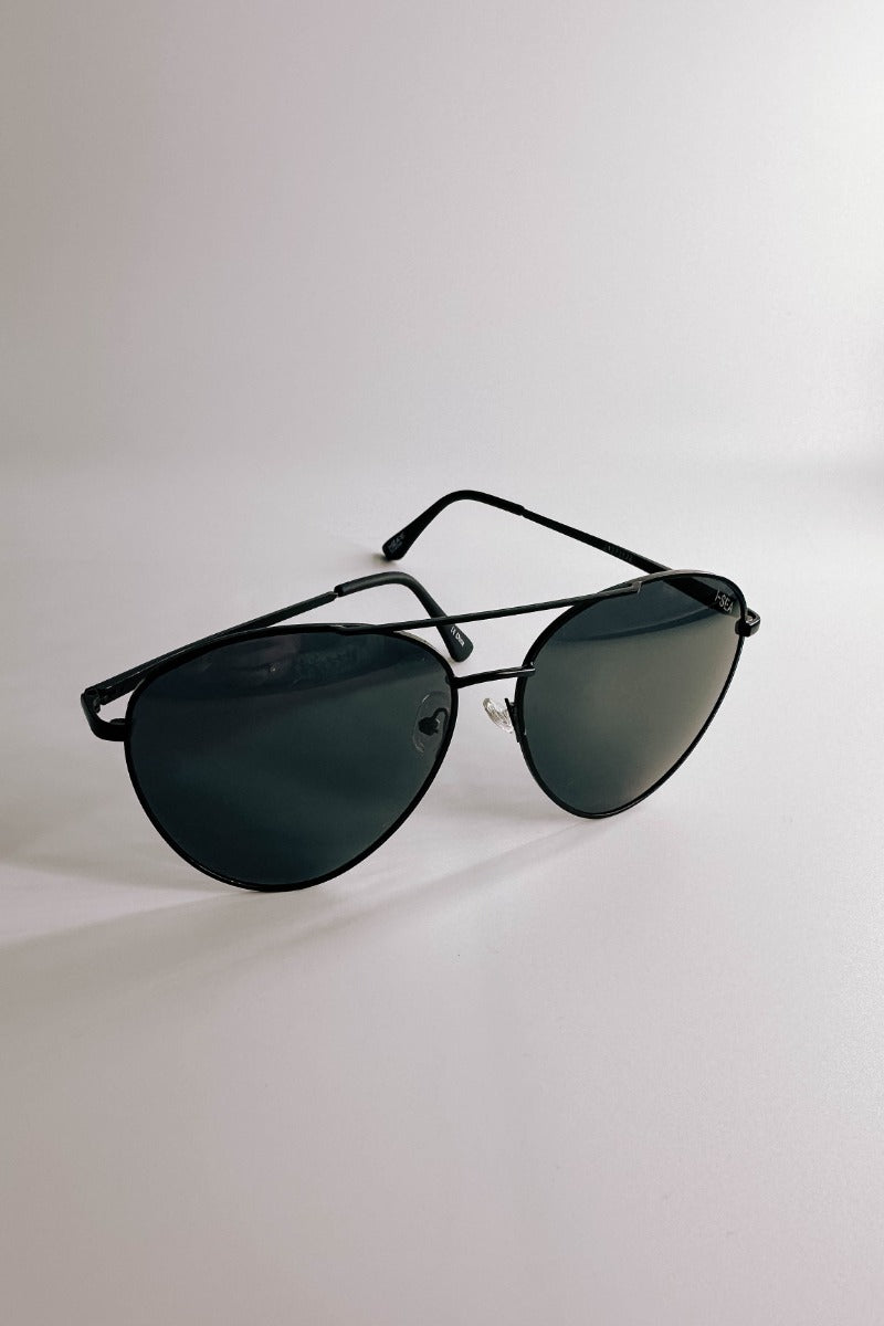 Front view of model wearing the I-Sea: Charlie Sunglasses in Black which features aviator shaped black frames and black lenses. 