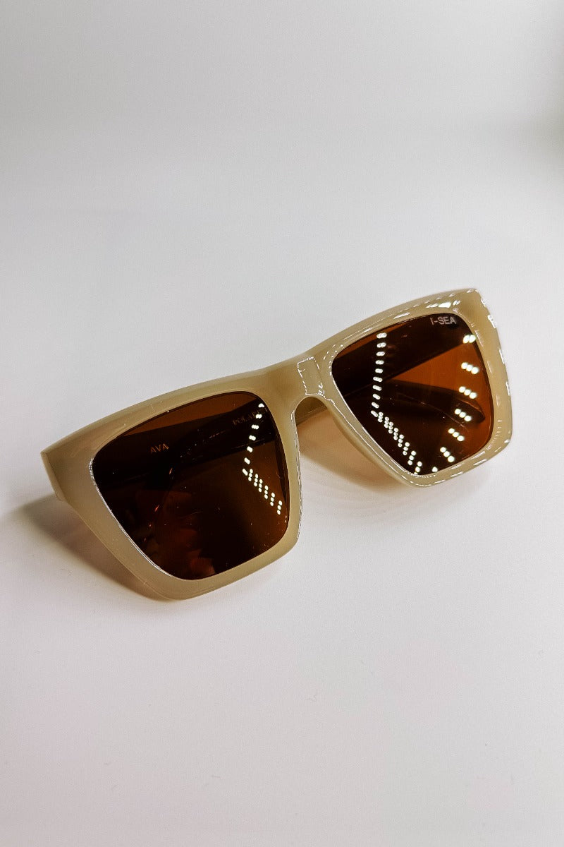 Front lay view of the I-Sea: Ava Sunglasses in Oatmeal & Brown which features light taupe frames with brown lenses.