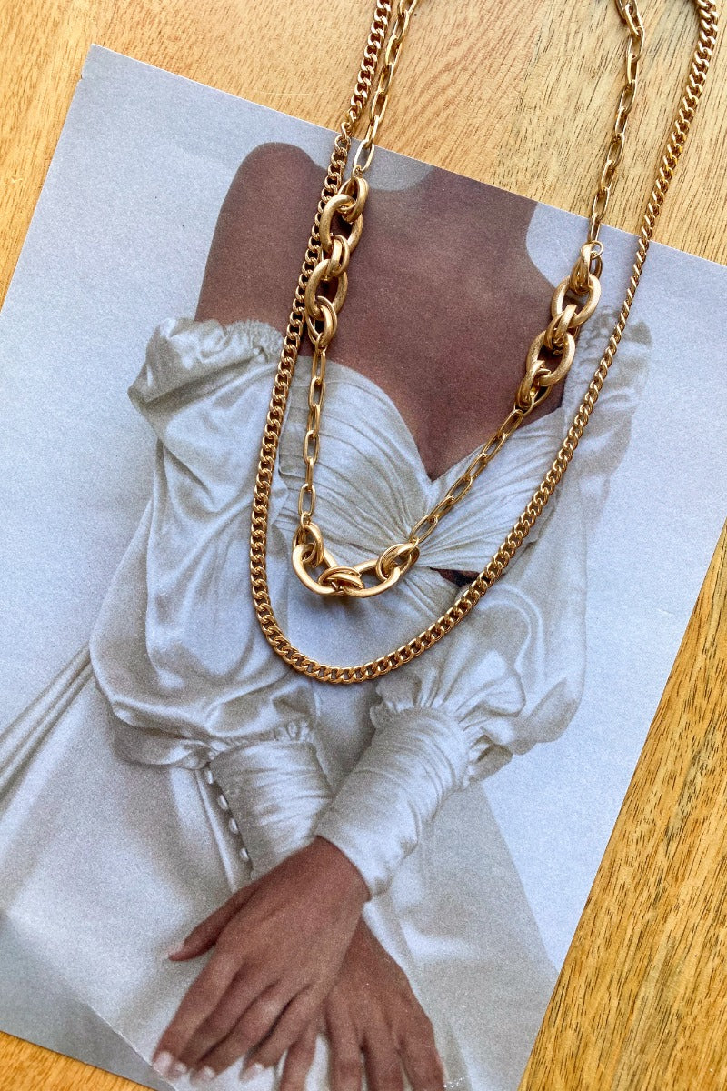 The Everyday Duo Necklace is a double layered necklace, featuring a gold chain and a gold chain link finished with an adjustable link and clasp closure.