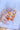 The Sweet Escape Earring is an acrylic dangle style earring featuring a three chain link design with one link a matte orange and the other two a clear orange ombre.
