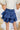Back view of the Maeve Skort that features a blue satin material, a thick elastic waist band with a tie detail, a ruffle tiered design, a shorts lining, and a mini length.
