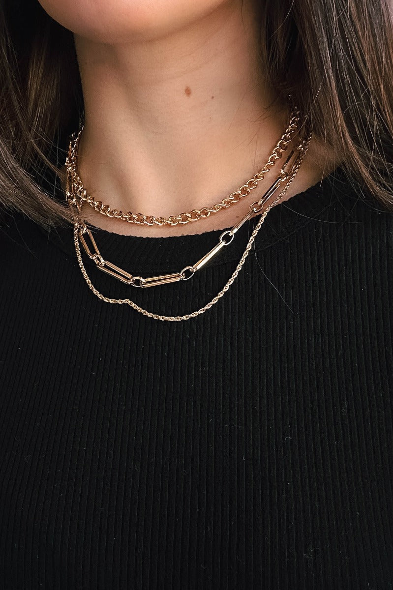 Front view of model wearing the Delilah Gold Chain Link Layer Necklace which features one gold roped layer, one gold chain layer and one gold rectangle chain layer.