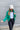 Front view of model wearing the Call It Even Puffer Jacket features green puffer fabric, two front pockets, a high neckline, a silver zip up, and long sleeves