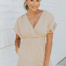 Frontal view of the Runaway Summer Romper that features a V neckline, a short cuffed sleeve, a ruched front, a cinched waist band, and a cuffed bottom hem.