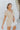 Frontal view of the Runaway Summer Romper that features a V neckline, a short cuffed sleeve, a ruched front, a cinched waist band, and a cuffed bottom hem.