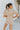 Back view of the Runaway Summer Romper that features a V neckline, a short cuffed sleeve, a ruched front, a cinched waist band, and a cuffed bottom hem.