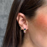 Front view of model wearing the Madison Multi Stone Gold Huggies which features mini gold hoops with multi color stones.