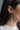 Side view of model wearing the Black Rhinestones Bow Shaped Dangle Earring which features bow shaped studs with black stones and black stone fringe details with gold trim.