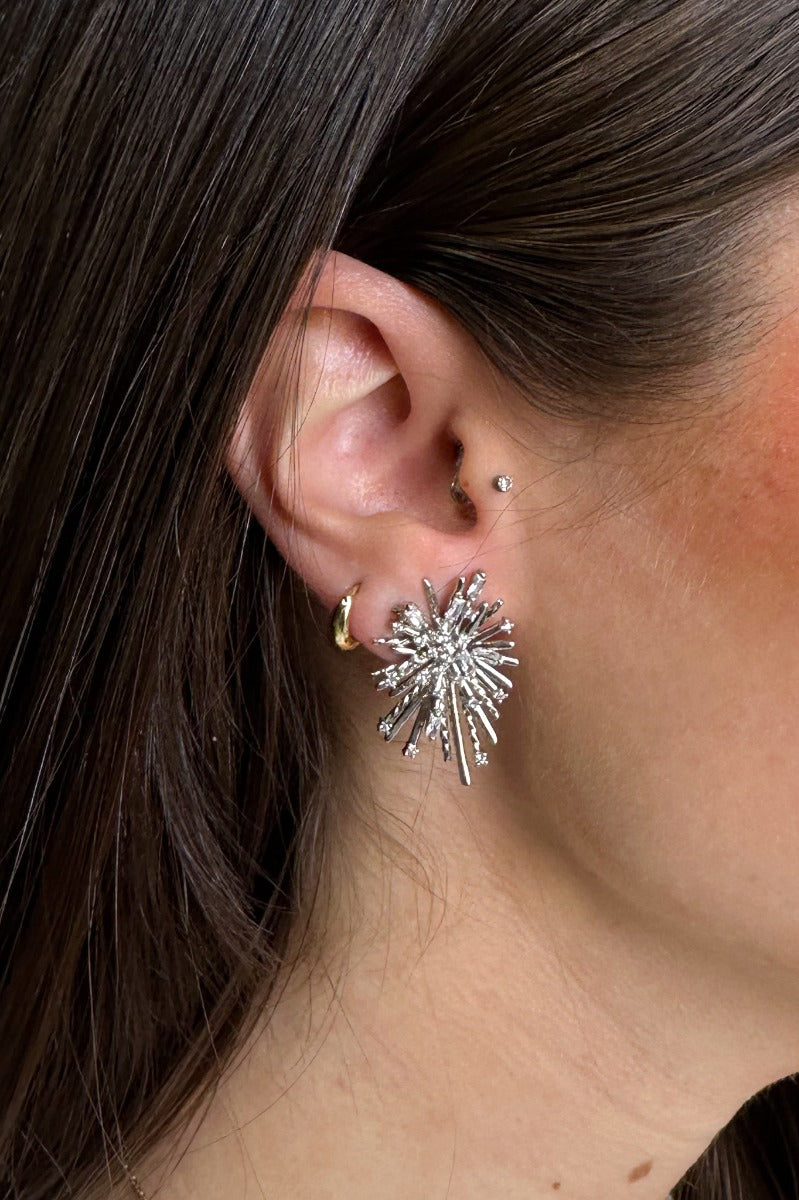 Side view o fmodel wearing the Ansley Rhinestone Silver Starburst Stud which features silver starburst design with clear stones.